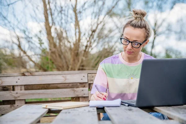 Die Blondine arbeitet bei schönem, sonnigem Wetter. Büro draußen. — Stockfoto