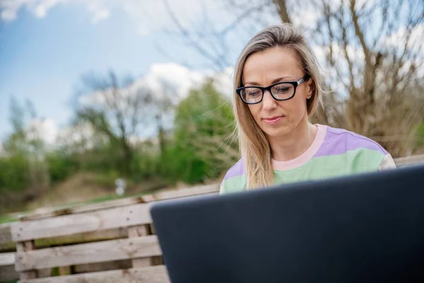 Frau mit Brille arbeitet draußen mit Laptop. Arbeiten außerhalb des Büros. — Stockfoto