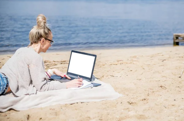 Kobieta pracująca nad jeziorem, używająca laptopa. Praca na własny rachunek. — Zdjęcie stockowe