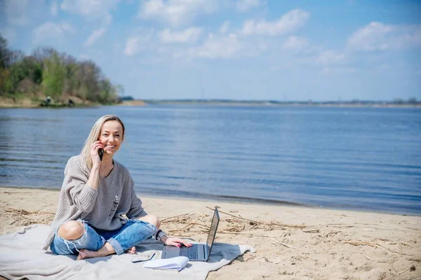 Glimlachend blond werkt op afstand op een mooie zonnige dag aan het meer. — Stockfoto