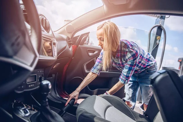 Eine Frau im karierten Hemd reinigt das Auto im Inneren. — Stockfoto