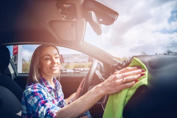 Lächelnde Frau reinigt mit Mikrofasertuch den Innenraum des Autos. — Stockfoto