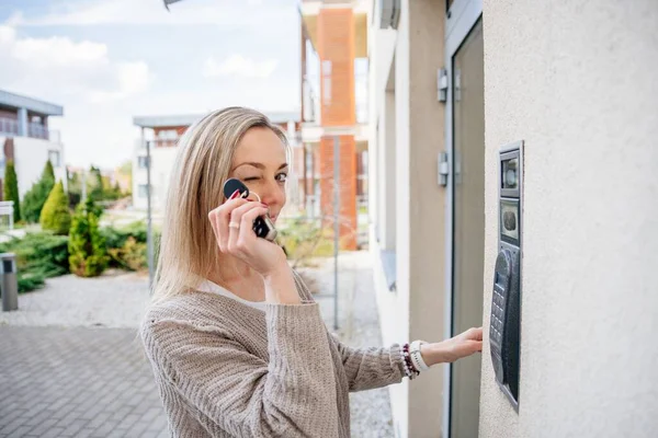 Femeia blondă face cu ochiul în timp ce ține telecomanda pentru a intra în casă . — Fotografie, imagine de stoc