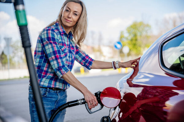 A woman at a gas station to refuel. Concept of departure, journey.