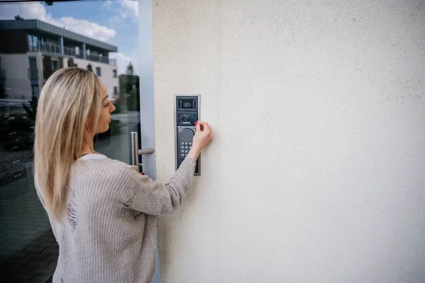 La mujer entra en el apartamento. Utiliza el mando a distancia para abrir la puerta. Imagen De Stock