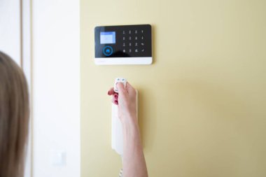 Giriş güvenlik sistemini çalıştırmak için uzaktan kumanda kullanan kadın el..