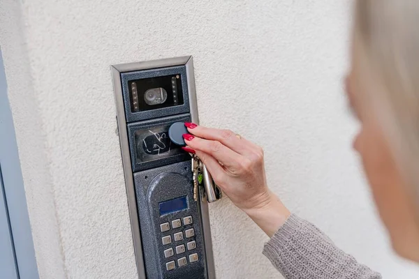 Uma mão de mulher usa um controle remoto para um alarme doméstico. — Fotografia de Stock
