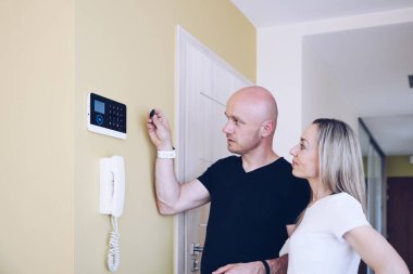 Tamirci güvenlik sistemi kuruyor. Kadın alarmı çalıştırmayı öğreniyor..