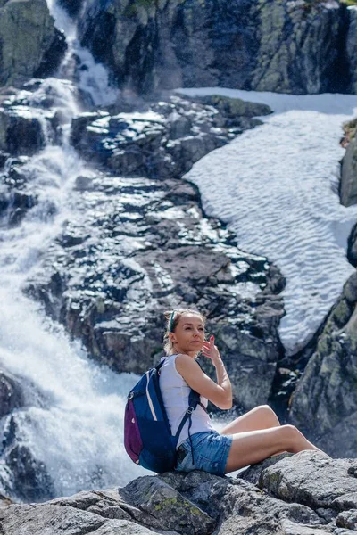 Un touriste blond est assis sur un rocher au-dessus de la cascade de Siklawa dans les montagnes polonaises Tatra. — Photo