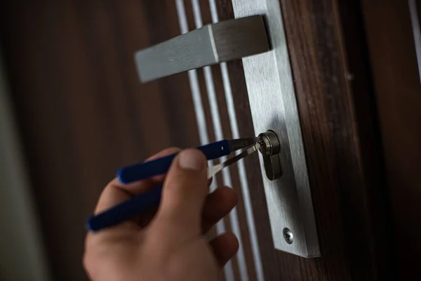 Thief opening a lock with picklock. A burglars hand with a lockpick. — Stock Photo, Image