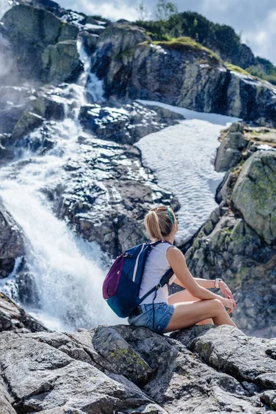 Female traveler admiring the view of the waterfall on a sunny day. — Stock Photo, Image