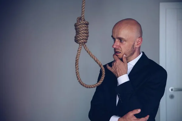 Um homem de negócios em um terno contempla cometer suicídio. — Fotografia de Stock