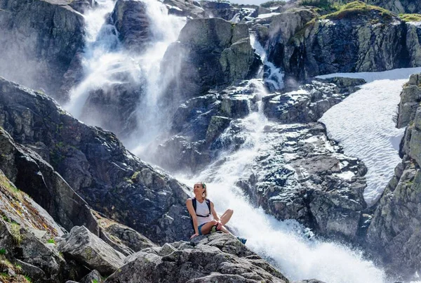 Belo turista está sentado em uma rocha acima da cachoeira Siklawa nas Montanhas Tatra polonesas. — Fotografia de Stock