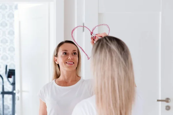 Bella ragazza che disegna il cuore su uno specchio in rossetto. — Foto Stock