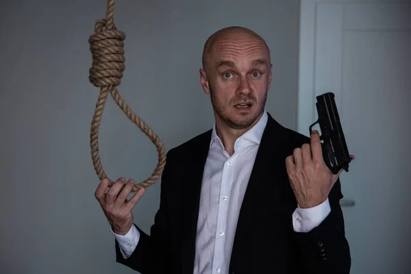 The man wants to commit suicide. He is holding a pistol in his hand, and a rope is hanging by it. — Stock Photo, Image