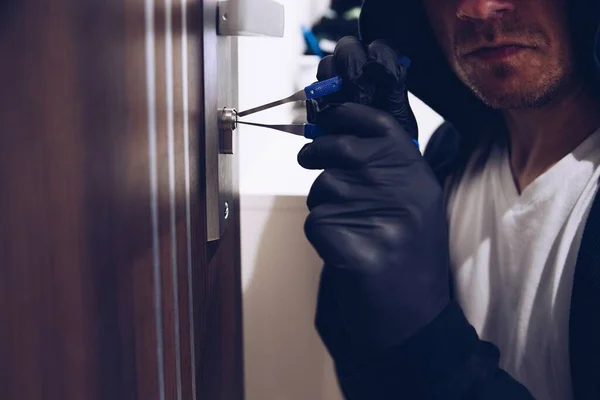Un ladrón abriendo una cerradura con un candado. Robar en casa. — Foto de Stock