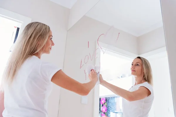 Donna positiva disegno a forma di cuore sullo specchio a casa. — Foto Stock