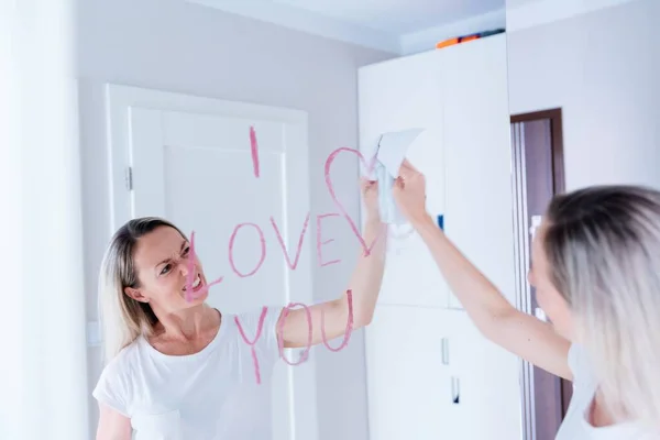 Žena otře nápis červené rtěnky ze zrcadla. — Stock fotografie