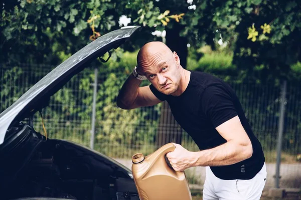 Hombre sorprendido comprueba el nivel de aceite del motor del coche. —  Fotos de Stock