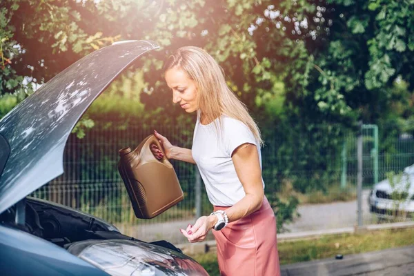 Eine Frau hält eine Flasche Motoröl in ihrem Auto. — Stockfoto