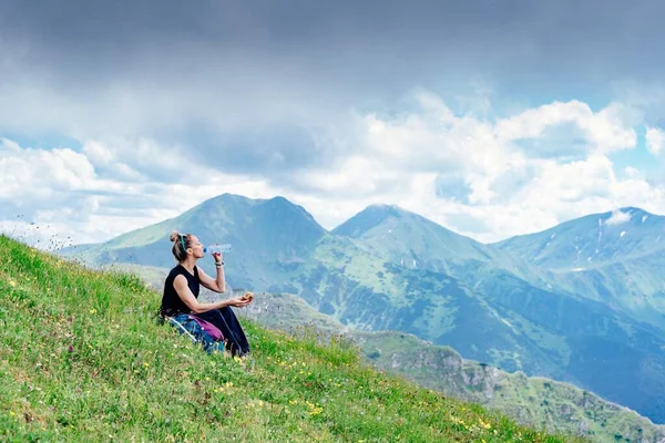 Mulher viajante bebe água com vista para a paisagem da montanha. — Fotografia de Stock