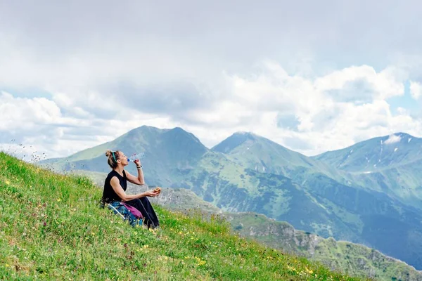 Um turista loiro está sentado na grama em belas montanhas polonesas. — Fotografia de Stock