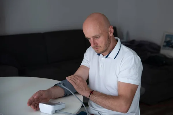 Hombre comprobando la presión arterial en su casa en la mañana. — Foto de Stock