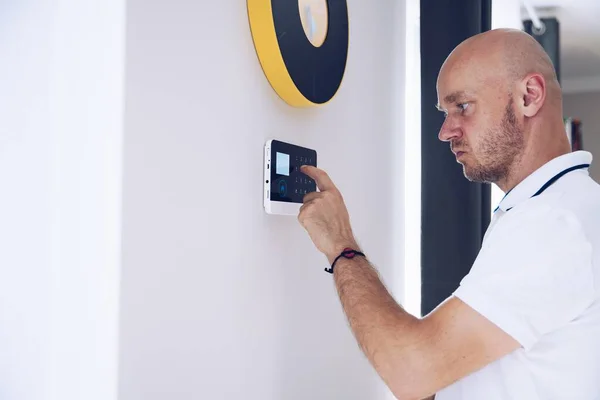 Homem armando um alarme doméstico na parede. — Fotografia de Stock