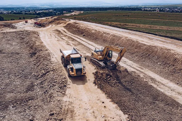 Vista aérea da escavadeira e caminhão basculante no local de construção. — Fotografia de Stock