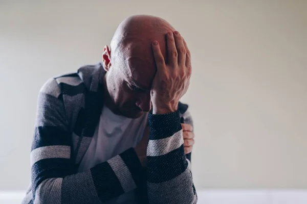 Hombre deprimido sentado en el sofá sosteniendo su cabeza. Piensa en sus problemas.. — Foto de Stock