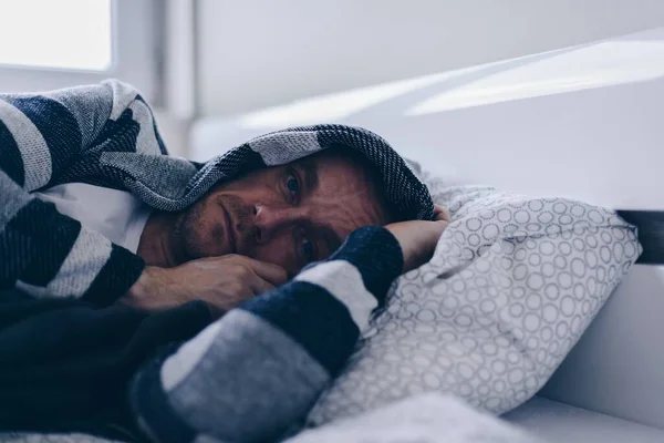 Hombre deprimido acostado en su cama y sintiéndose mal. — Foto de Stock