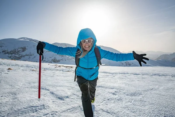 Female alpinist with arms outstretched and with ice axe in hand on the mountain summit. — Φωτογραφία Αρχείου