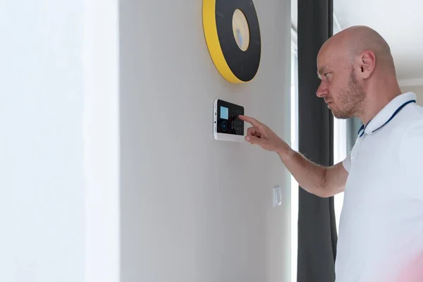 Um homem pressiona botões no painel de controle para desarmar o sistema de alarme anti-roubo. — Fotografia de Stock
