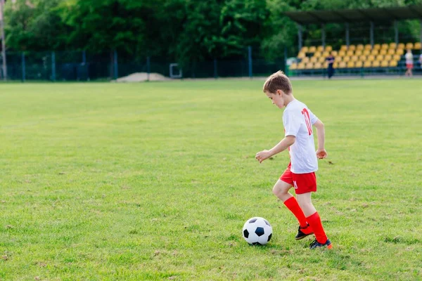 8 years old boy child playing football on playing field. — Stock Photo, Image