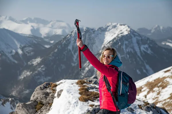 Female tourist on top of a mountain with a raised hand holding an ice ax. — Φωτογραφία Αρχείου