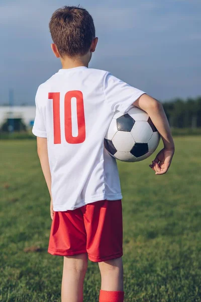 Bagudrettet billede af en lille fodboldspiller. Aktiv livsstil koncept. - Stock-foto