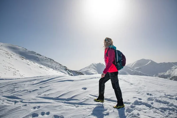 Жінка-туристка в червоній куртці відправляється в гірську стежку в красивий зимовий день . — стокове фото