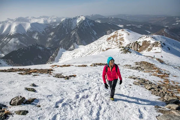 Blonde woman in the red jacket and black pants with sunglasses is goes beautiful mountain trail. — Φωτογραφία Αρχείου