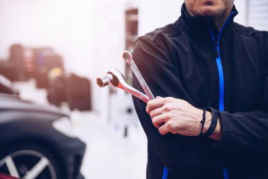 Araba tamircisi İngiliz anahtarı tutuyor.