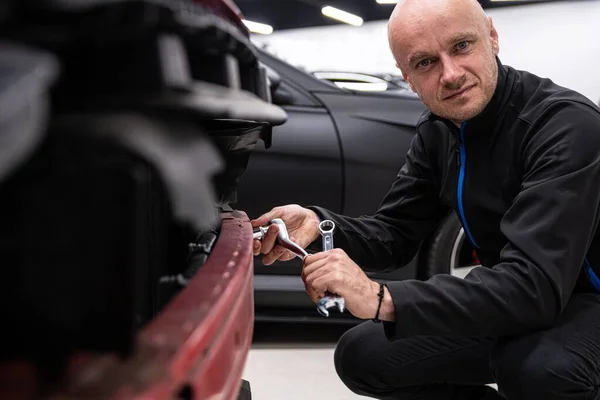 Mechanic in service checking and repairing car bumper — Stok fotoğraf