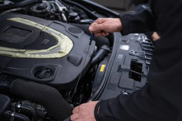 Mechanic checking oil level in car service — Stok fotoğraf