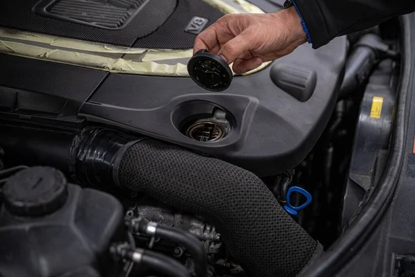 Service mechanic holding oil cap near engine. — Stockfoto