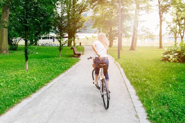 Vue arrière de la femme faisant du vélo de ville dans le parc de la ville, jour d'été. — Photo