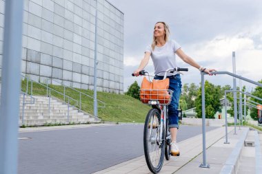Güzel ve neşeli bir kadın, güneşli şehir dışında bisiklet sürmekten zevk alıyor..