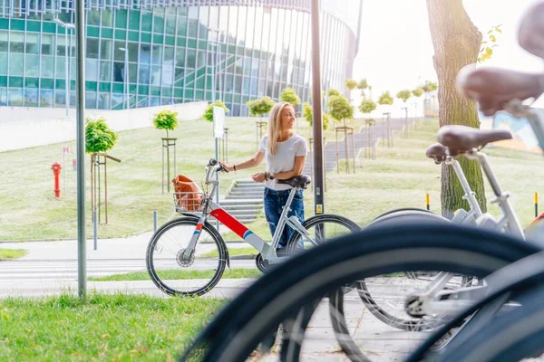 Uśmiechnięta dorosła kobieta jeździ rowerem miejskim po mieście. — Zdjęcie stockowe
