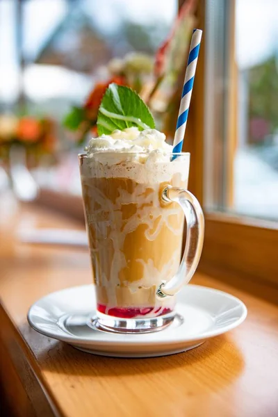 Latte coffee in a tall glass with whipped cream and mint leaf. — Stock Photo, Image