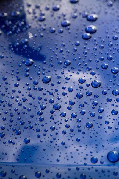 Gotas de chuva em um corpo de carro azul com efeito hidrofóbico. — Fotografia de Stock