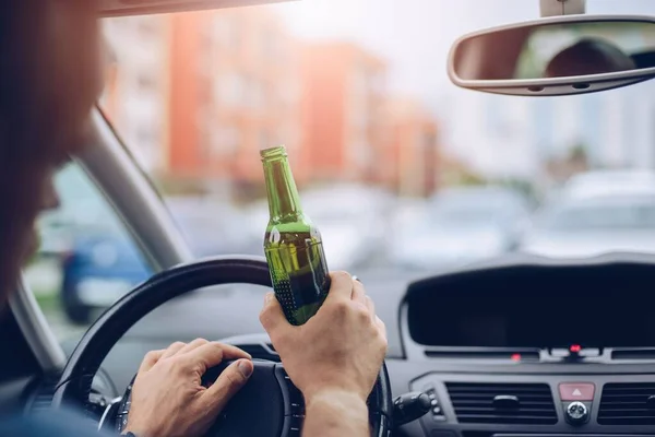 Hombre adulto borracho conduce un coche con una botella de cerveza. — Foto de Stock