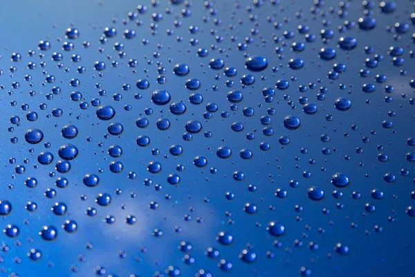 Gotas de lluvia en una carrocería azul con efecto hidrofóbico. — Foto de Stock