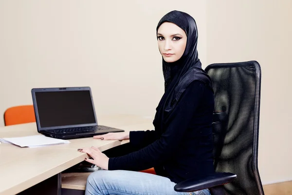 Muslimska hijab bäraren kvinna sitter vid ett skrivbord med en dator — Stockfoto